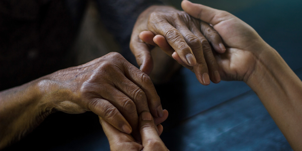 Youthful looking hands holding hands with elderly looking hands