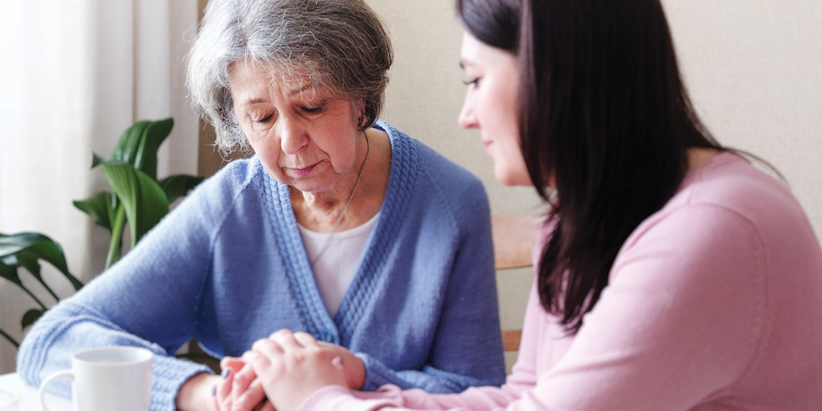 elderly, solemn woman holding hands with younger woman