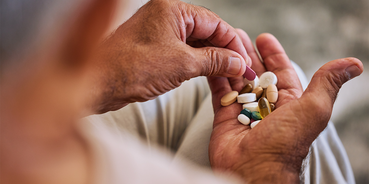 elderly pair of hands holding 15+ different medications