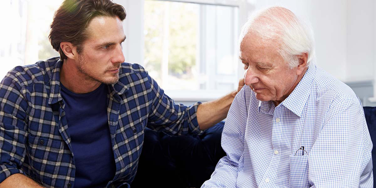 Young man showing care and concern to elderly man