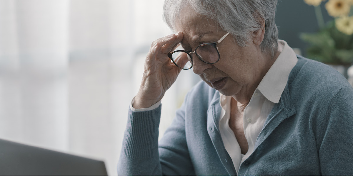 elderly woman with hand on brow