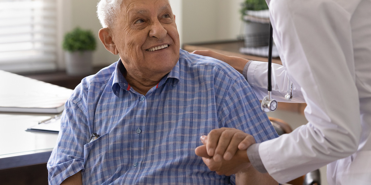 elderly man smiling up at medical professional
