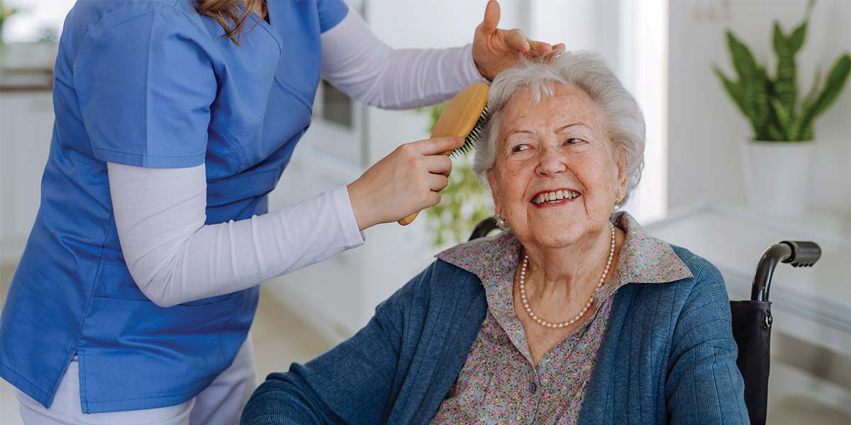 caretaker brushing elderly woman's hair