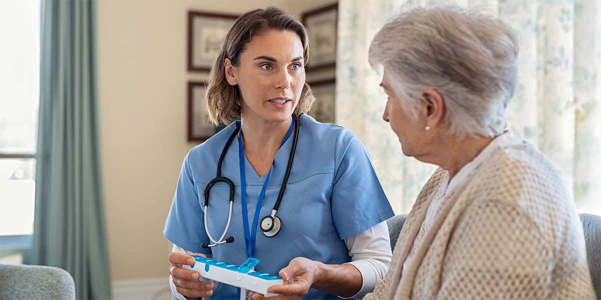 older adult woman facing medical professional who is holding weekly pull box