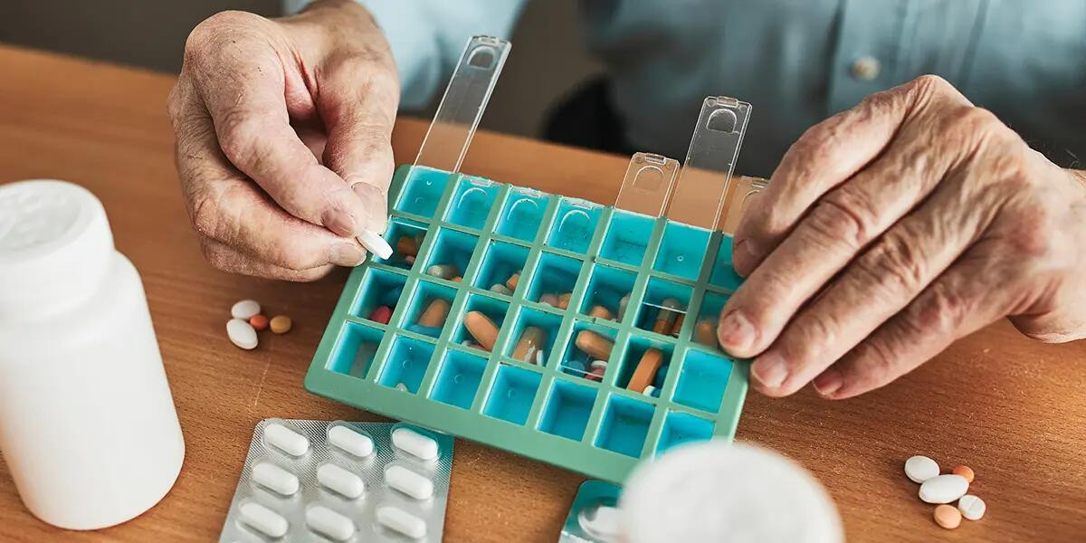 medication box being loaded by elderly person