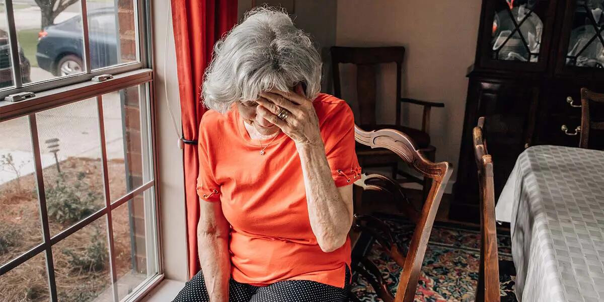 elderly woman with hand on forehead