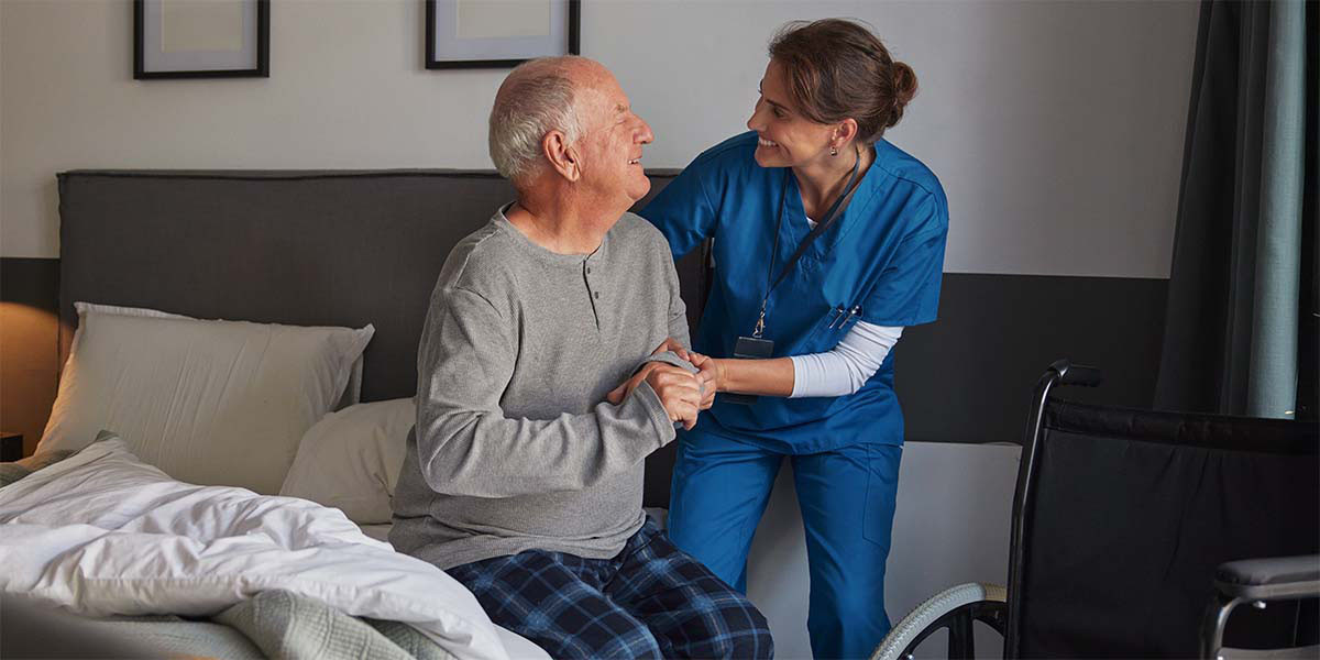 healthcare worker helping older adult male into wheelchair