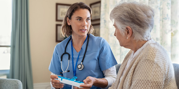 older adult woman facing medical professional who is holding weekly pull box