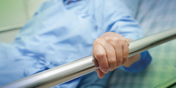 person in hospital bed with hand on the rail