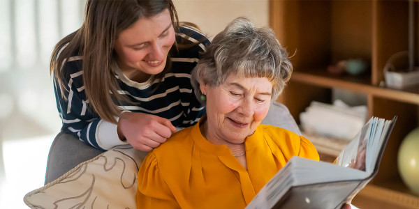 smiling woman looking over the shoulder of smiling older adult woman
