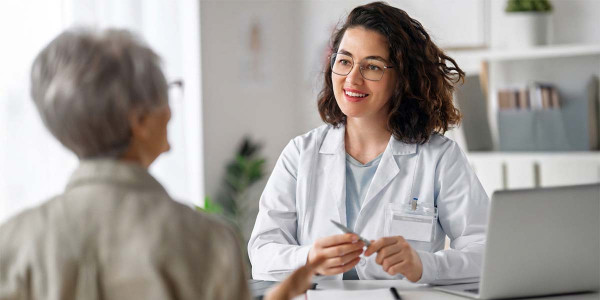 seated older adult at desk facing a smiling medical personnel