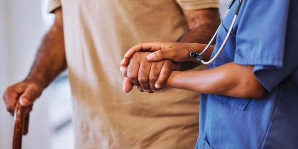 Elderly gentlemen with cane being helped by healthcare worker