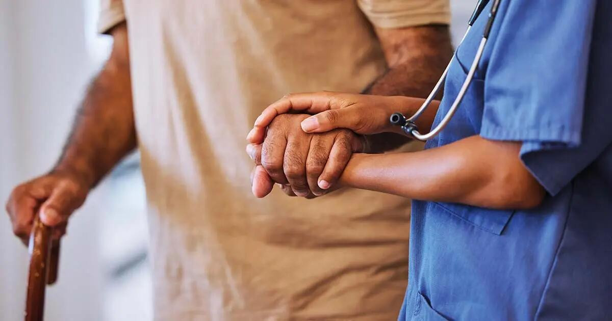 Elderly gentlemen with cane being helped by healthcare worker