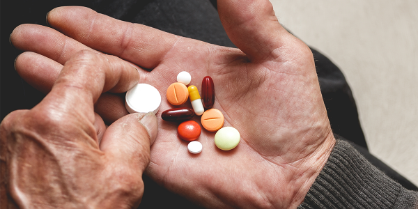 elderly person holding an assortment of medications