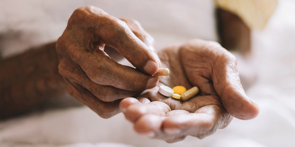 elderly hands holding several medications