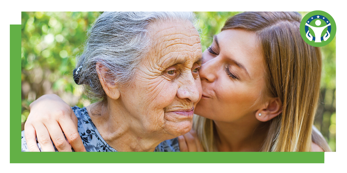 elderly woman and younger caregiver sharing affection as younger woman kisses elderly woman on cheek