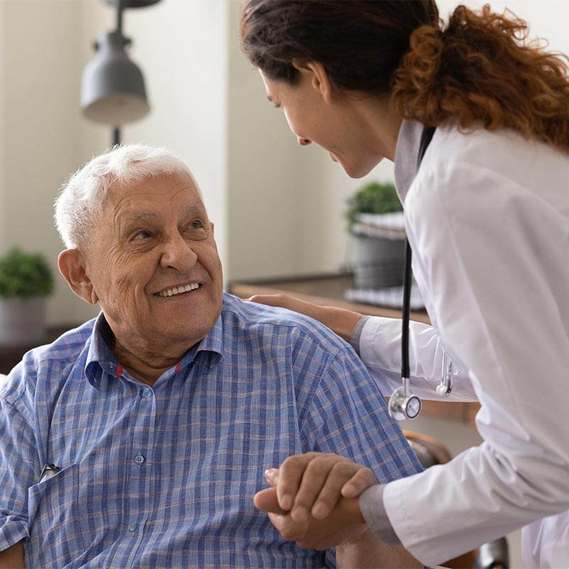 An older man smiles at a doctor
