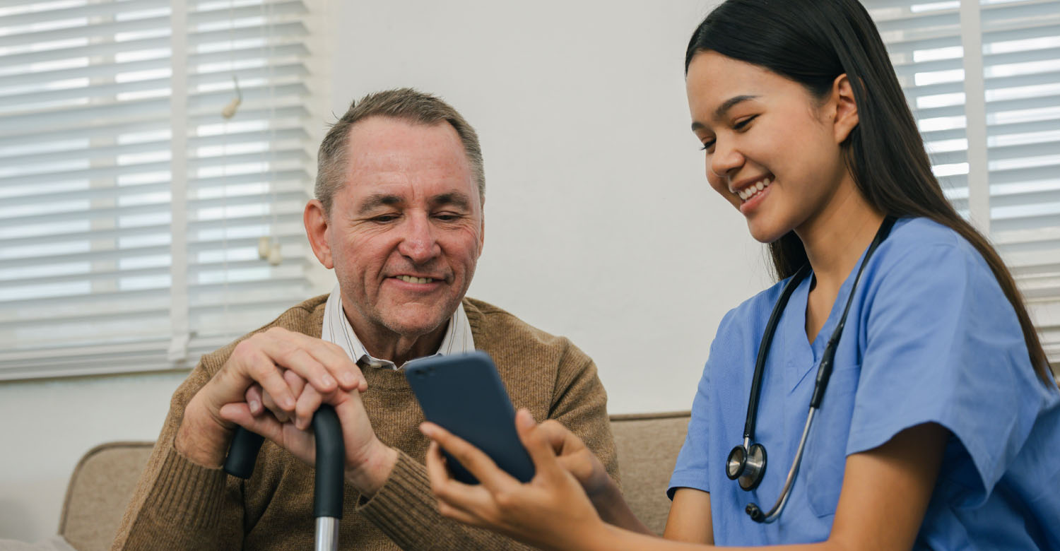 Older adult man seated with medical professional looking at screen